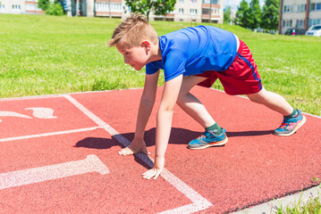 Caucasian boy,kid prepare to start running on a red track.young boy in starting position ready for...