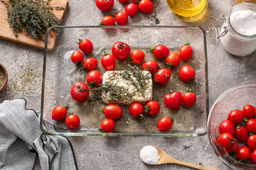 Baking dish with fresh tomatoes, feta cheese and spices on grunge background