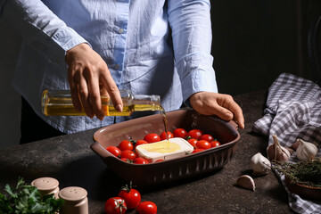 Obraz na płótnie Canvas Woman preparing tomatoes and feta cheese for baking in kitchen