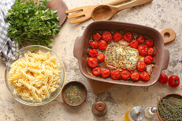 Baking dish with roasted tomatoes, feta cheese, pasta and spices on grunge background