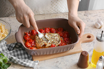 Woman preparing tomatoes and feta cheese in kitchen