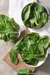 Bowls with fresh spinach leaves on grunge background