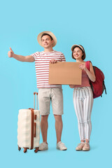 Obraz premium Young couple with cardboard hitchhiking on color background