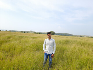 Naklejka na ściany i meble Indian young man, person on a meadow, young man in the wild, people in field. 