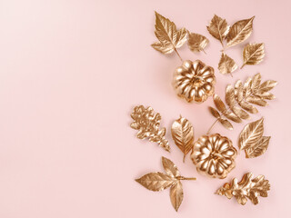 Gold autumn leaves on pink background. Autumn concept. Top view of autumn leaves in gold paint on...