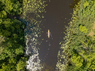 Kayak on a narrow river with green banks in summer. Aerial drone view.
