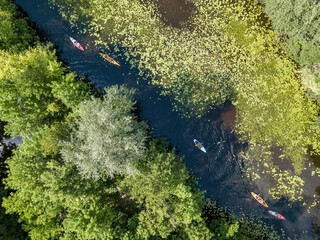 Kayak on a narrow river with green banks in summer. Aerial drone view.