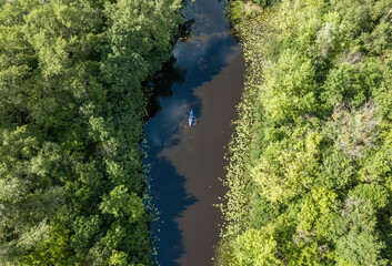 Kayak on a narrow river with green banks in summer. Aerial drone view.