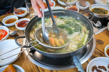 Korean food: Galmi Shabu Shabu with fresh raw Surf clam, kimchi, side dishes, and udon noodles