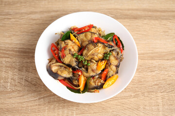 Stir fried spicy cat fish in white dish on wooden table
