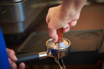 barista holds a press for freshly ground coffee beans for making coffee
