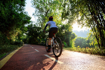Woman cycling on bike path at sunrise park
