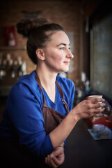 Female barista inspecting a perfect coffee in a paper cup
