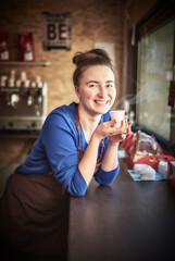Female barista inspecting a perfect coffee in a paper cup
