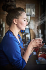 Female barista inspecting a perfect coffee in a paper cup