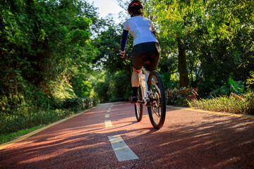 Naklejka premium Woman cycling on bike path at sunrise park