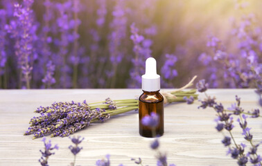 Essential lavender oil in the bottle with dropper on the gray wooden desk. Horizontal close-up.