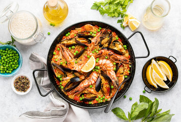 Seafood paella ready to eat served in a paella pan, top-down view - obrazy, fototapety, plakaty