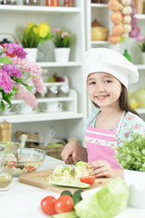 Cute girl preparing delicious fresh salad in kitchen