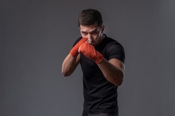 Focused young fighter with wrapped hands standing in orthodox stance