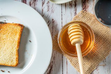 Preparing a healthy breakfast with a toast with butter and pure organic honey from bees.