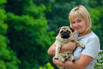 Woman with a pug dog in her arms.
