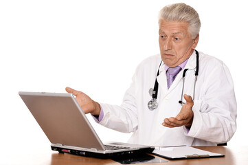 Elderly doctor with a laptop on white background