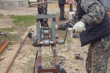 Workers bend metal in a pipe bender.