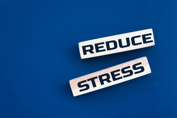 Wooden blocks with Reduce Stress text and blue background. Concept image to keep calm and stop worrying. Healthcare concept.