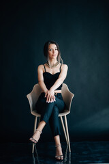 Beautiful woman sits on a chair and looks at you