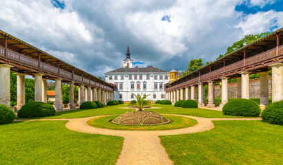 Lysice castle, Czech Republic. Famous baroque castle built in 14th century. Beautiful formal garden, palm trees and flowers. Promenade near the castle. Sunny day, dramatic clouds before storm.