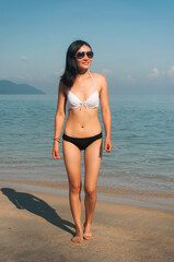 happy chinese woman wearing a bikini on a beach