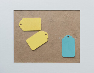 two yellow and one blue pastel colored retro wooden tags on paper background with accent frame