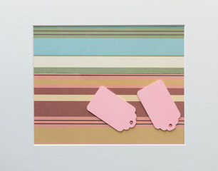 two baby pink pastel-colored retro wooden tags on a striped paper background with accent frame