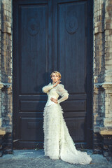 Blonde girl in a retro dress on the background of the old dark door