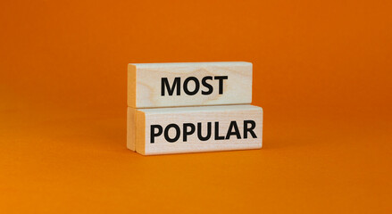 Most popular symbol. Concept words Most popular on wooden blocks on a beautiful orange background. Copy space. Business and Most popular concept.