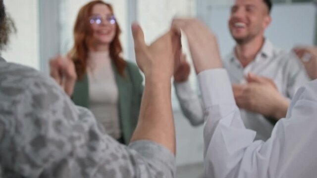 motivational session, young men and women staff holds hands and sweeps his hands up then claps his hands during business training to raise corporate spirit