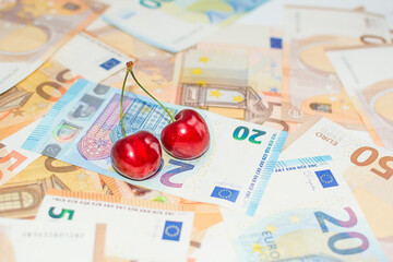 pair of cherries on a carpet of banknotes, concept of the increase in fruit prices