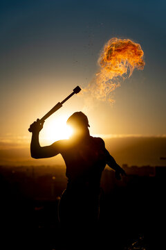 Fire-eater artist performing spit fire at sunset