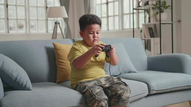 Serious Boy Playing Computer Game With Joystick In Living Room, Feeling Unhappy With His Loosing Game
