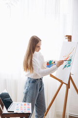 Young female artist painting picture in studio
