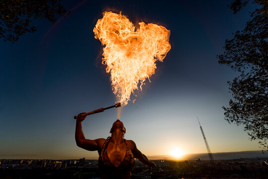 Fire-eater artist performing spit fire at sunset