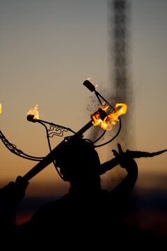 Fire-eater artist performing spit fire at sunset