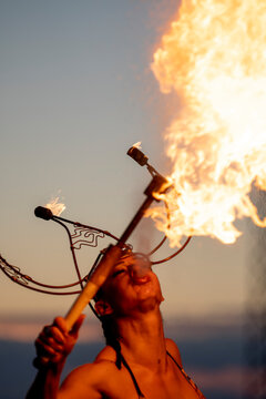Fire-eater artist performing spit fire at sunset