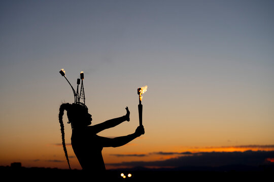 Fire-eater artist performing spit fire at sunset