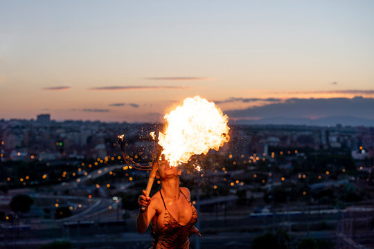 Fire-eater artist performing spit fire at sunset