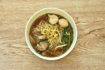 Chinese egg noodles topping braised pork and meatball in brown soup on bowl