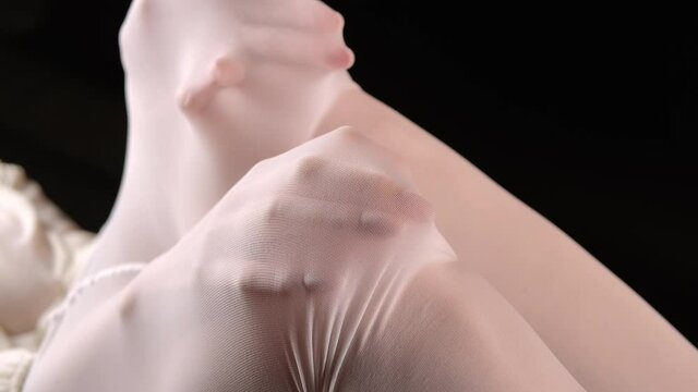 Footage of female hands under white nylon tights