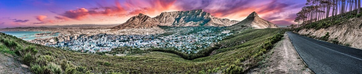 Dramatic and colourful sunset panorama of Table Mountain and the city bowl area, Cape Town South Africa. A unique wide-angle perspective from Signal Hill road  including some forest environment