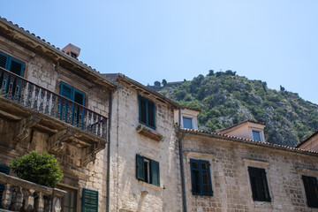 Fototapeta na wymiar Old town of Kotor Montenegro on the background of mountains and blue sky. The bright beautiful landscape of against the background of mountains in the summer on a clear day